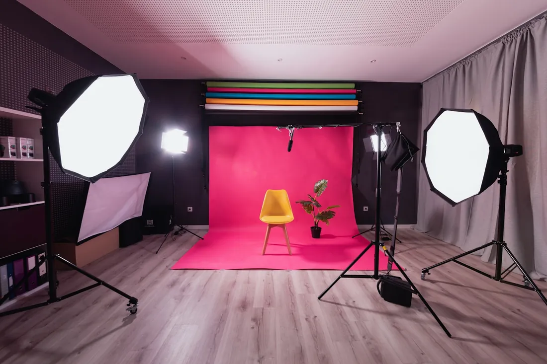 Malé natáčecí studio s křeslem, rostlinou a rozestavěnou technikou mimo hlavní záběr